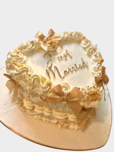 heart-wedding-cake-essex-gold-bows Heart-shaped vintage style cake with cream buttercream, gold details and Just Married topper